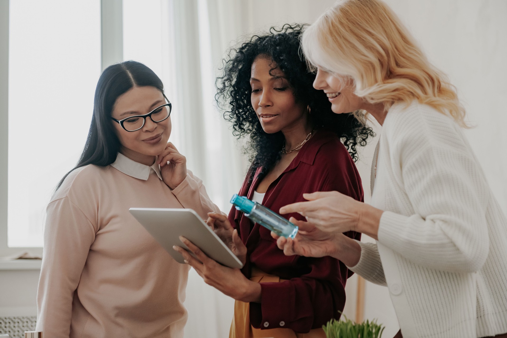 Three confident mature women buying beauty products online while spending time together