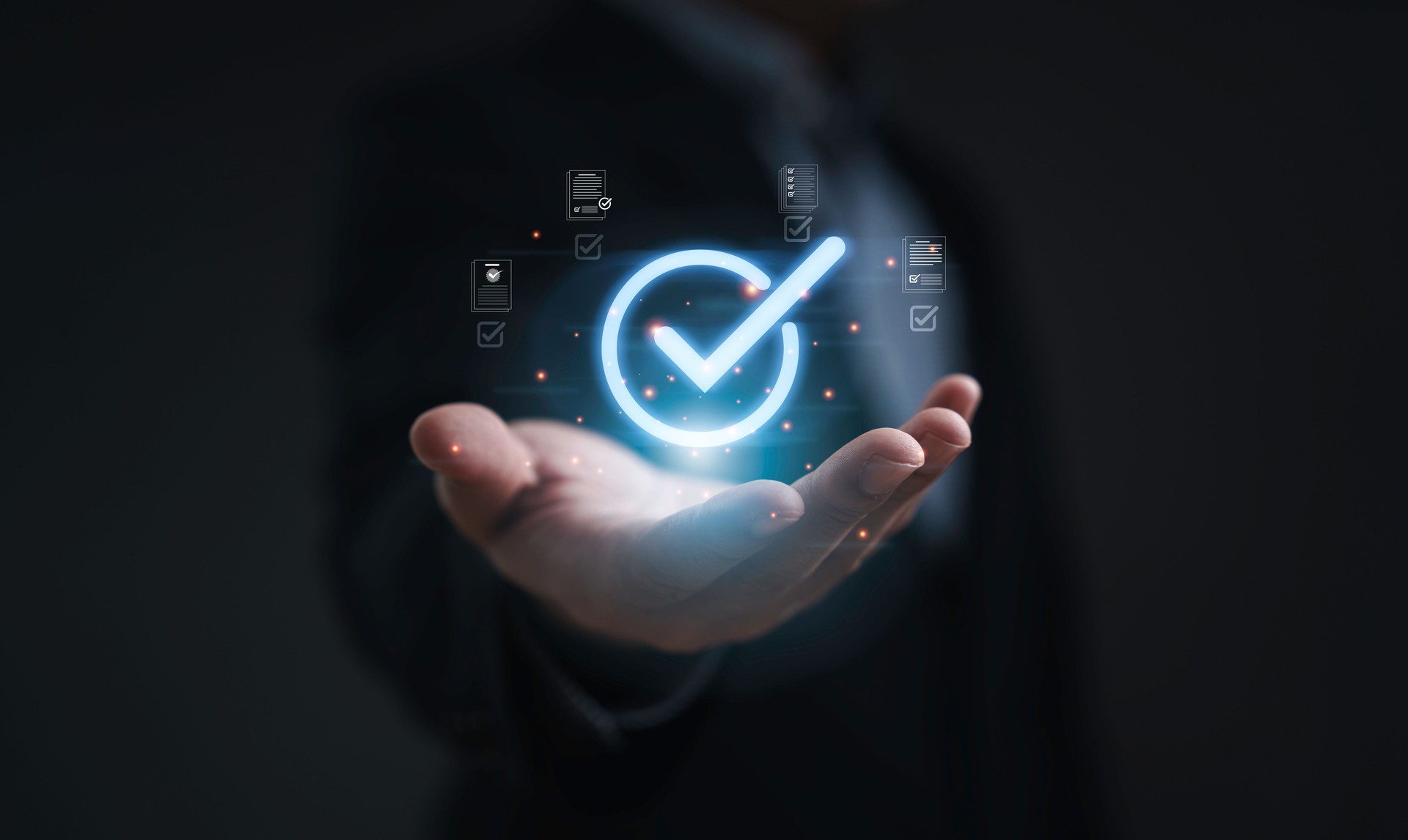 Businessman hand holding glowing check mark symbol with digital document icons representing approval process quality control verification and business success on dark background